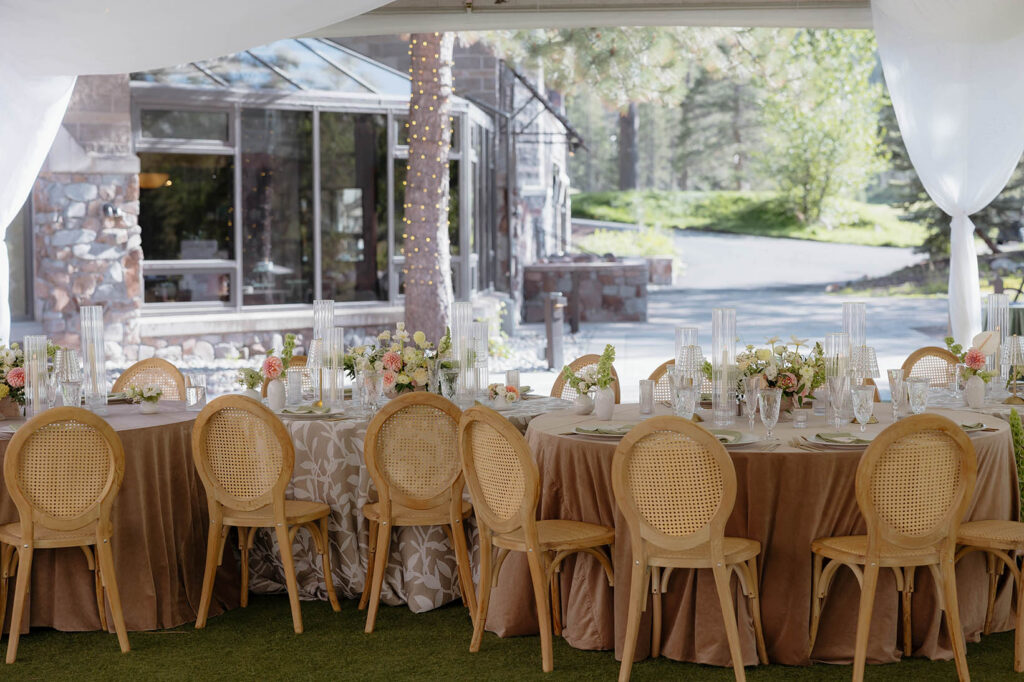 Wedding reception table with neutral colors and floral bouquets and wooden chairs with silk drapes at Everline Resort at Lake Tahoe