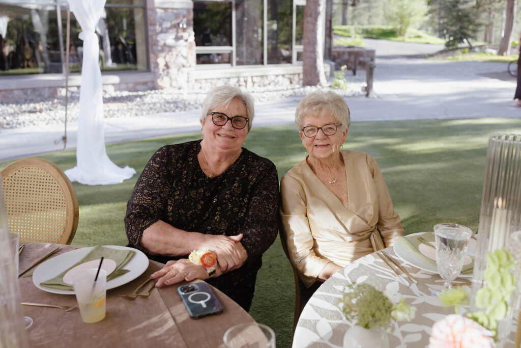 Wedding guests smiling at camera while sitting next to each other at reception table at Everline Resort in Lake Tahoe