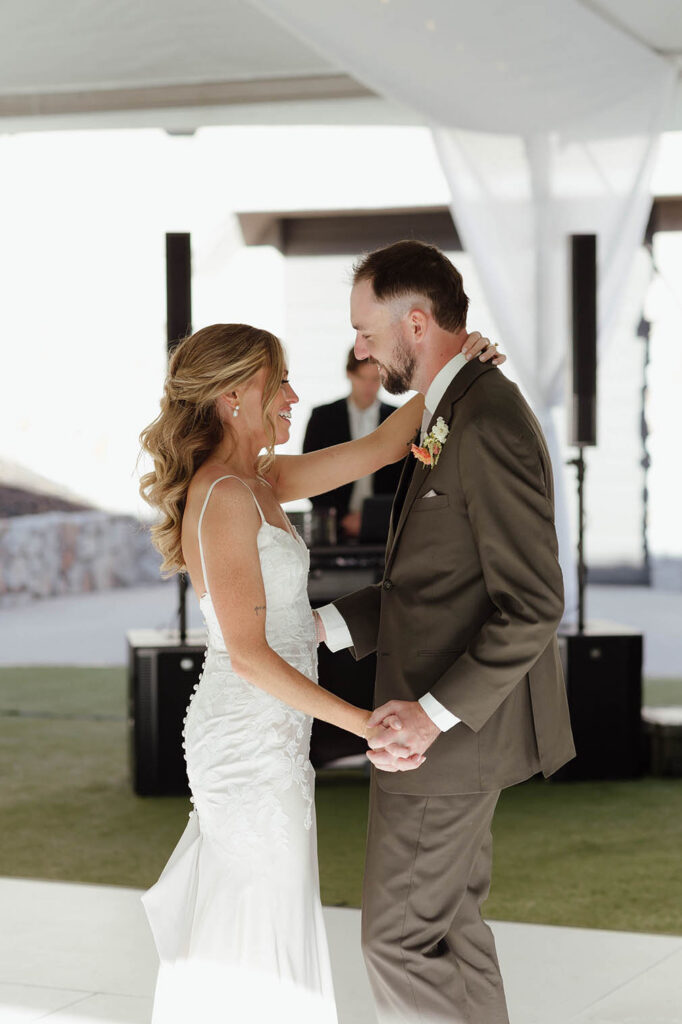 Wedding couple holding hands and dancing while smiling at each other during reception first dance at Everline Resort at Lake Tahoe