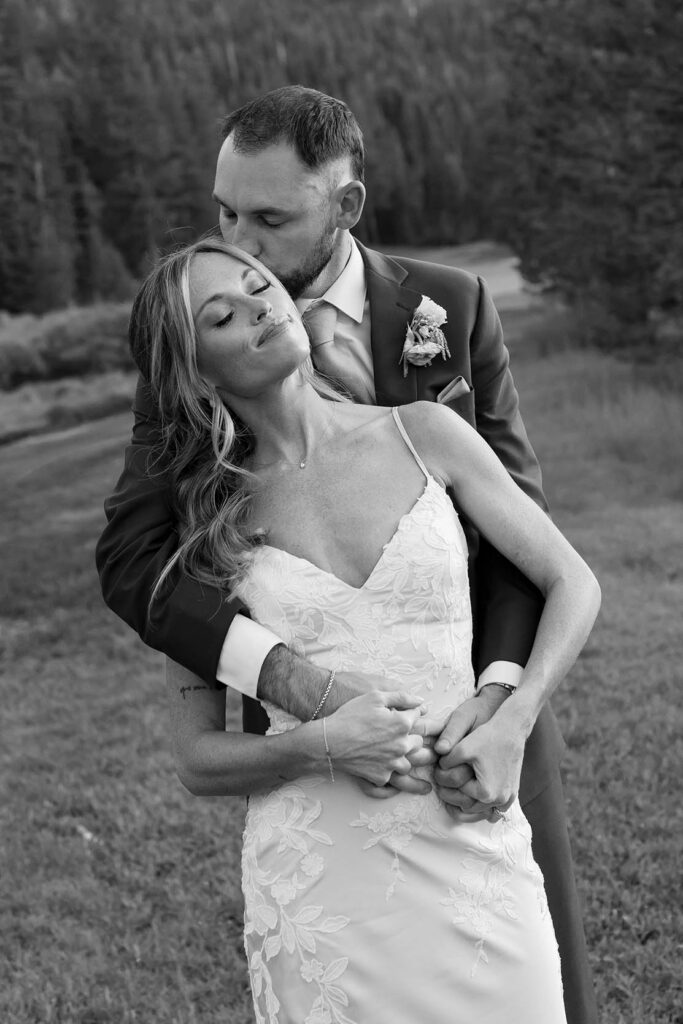 Groom hugging Bride from behind while kissing her head at Everline Resort in Lake Tahoe