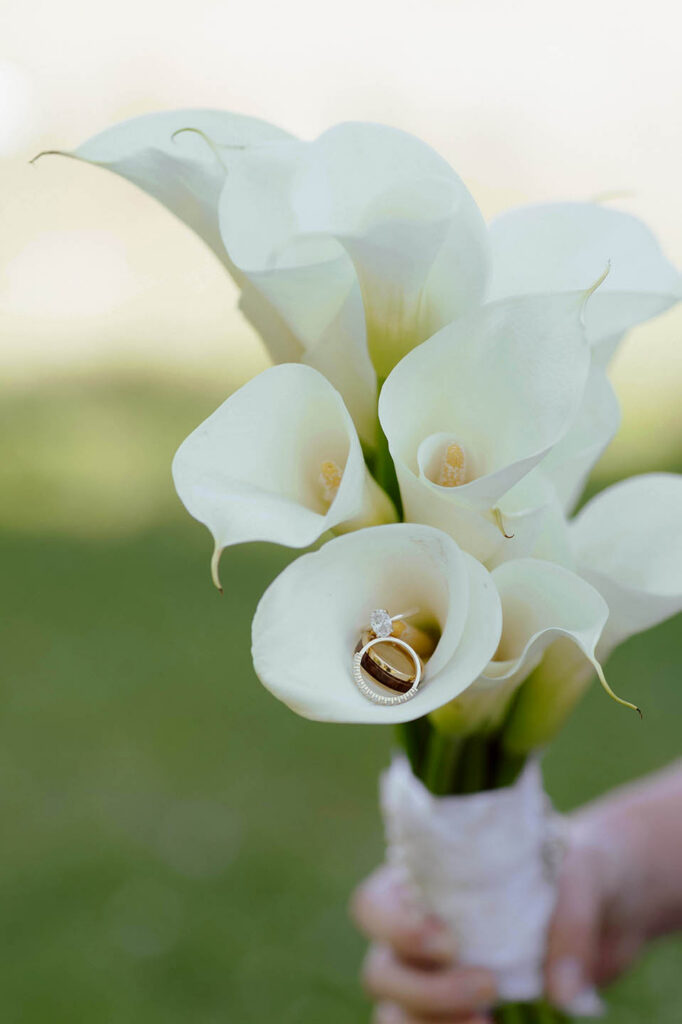 Wedding rings inside flower in white floral bouquet at Kinship Ranch