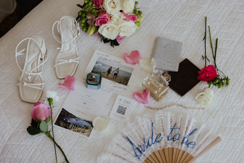 White heels, pink and white flowers, rings, invitations, perfume, and vows arranged for an Emerald Bay Lake Tahoe elopement
