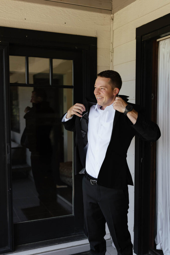 Groom putting on his black suit jacket before the Emerald Bay wedding ceremony