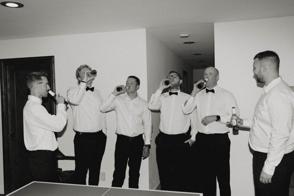 Black-and-white candid photo of the groomsmen drinking beers before the Lake Tahoe elopement