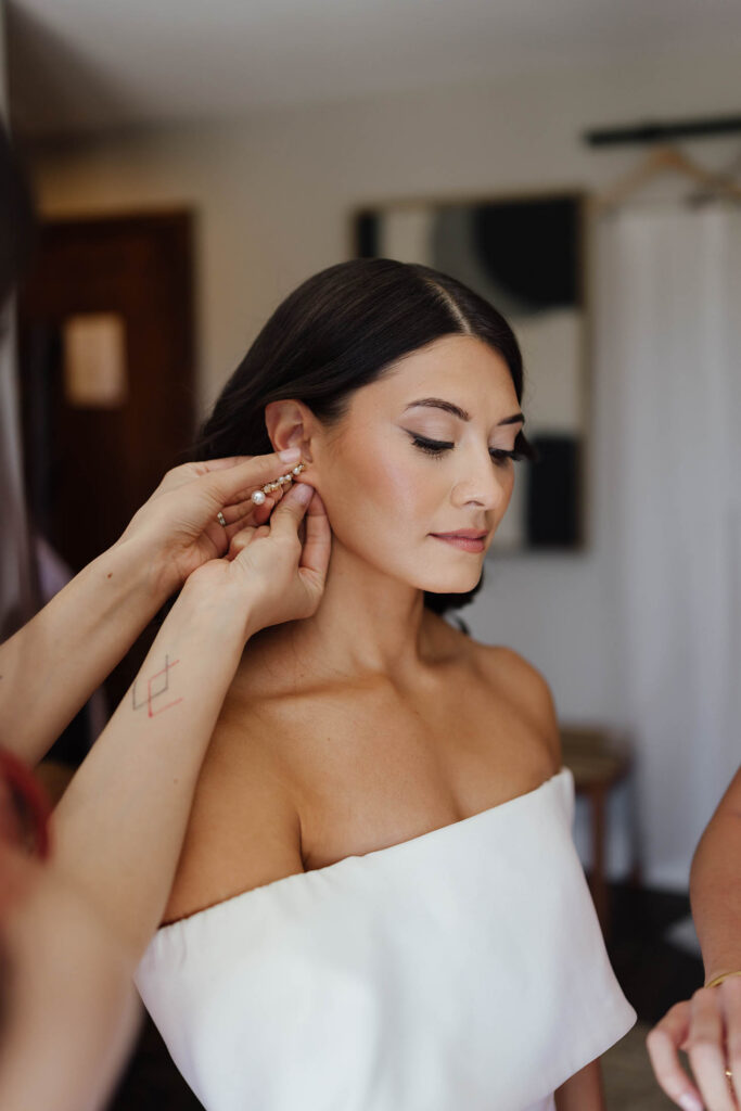 A bridesmaid fastens the bride’s pearl earring as she gets ready for her Lake Tahoe elopement