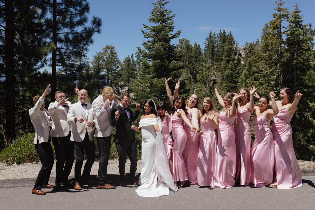 The bride, groom, bridesmaids, and groomsmen celebrate together beneath the Lake Tahoe pine trees