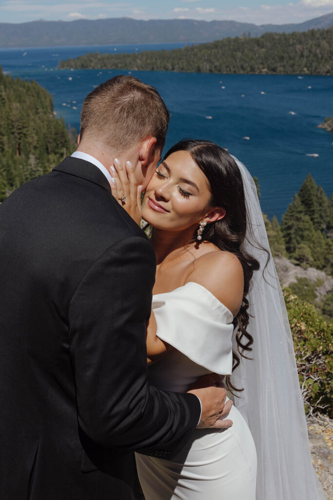 The bride embraces the groom with Emerald Bay and the Lake Tahoe mountains behind them