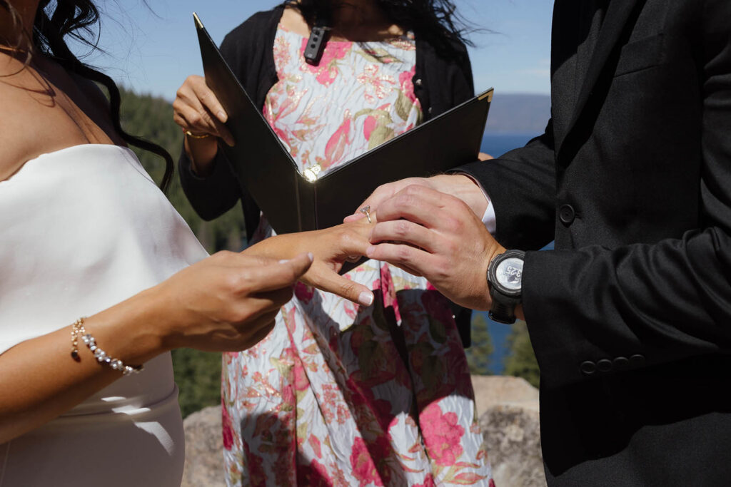 The groom places a wedding ring on the bride’s finger during their Lake Tahoe elopement ceremony