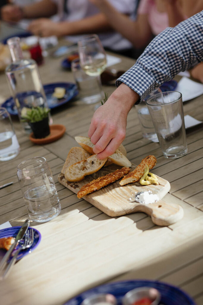 A guest reaches for bread from a shared appetizer board during the reception at Primo’s