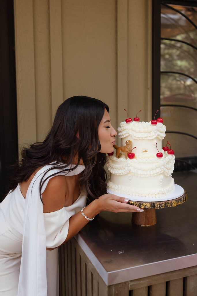 The bride playfully kisses the golden retriever topper on her custom wedding cake