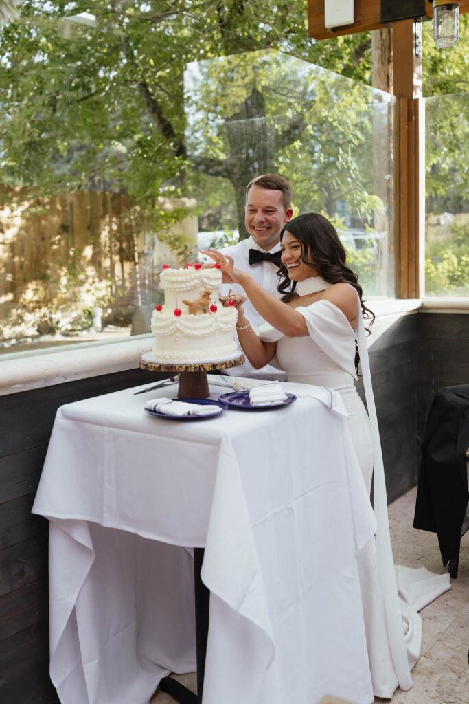The bride and groom laugh together while cutting their cake at the Lake Tahoe wedding reception