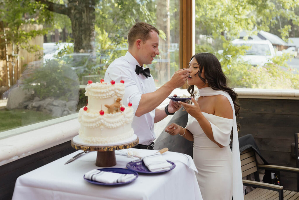 The groom feeds the bride a bite of wedding cake during their reception at Primo’s