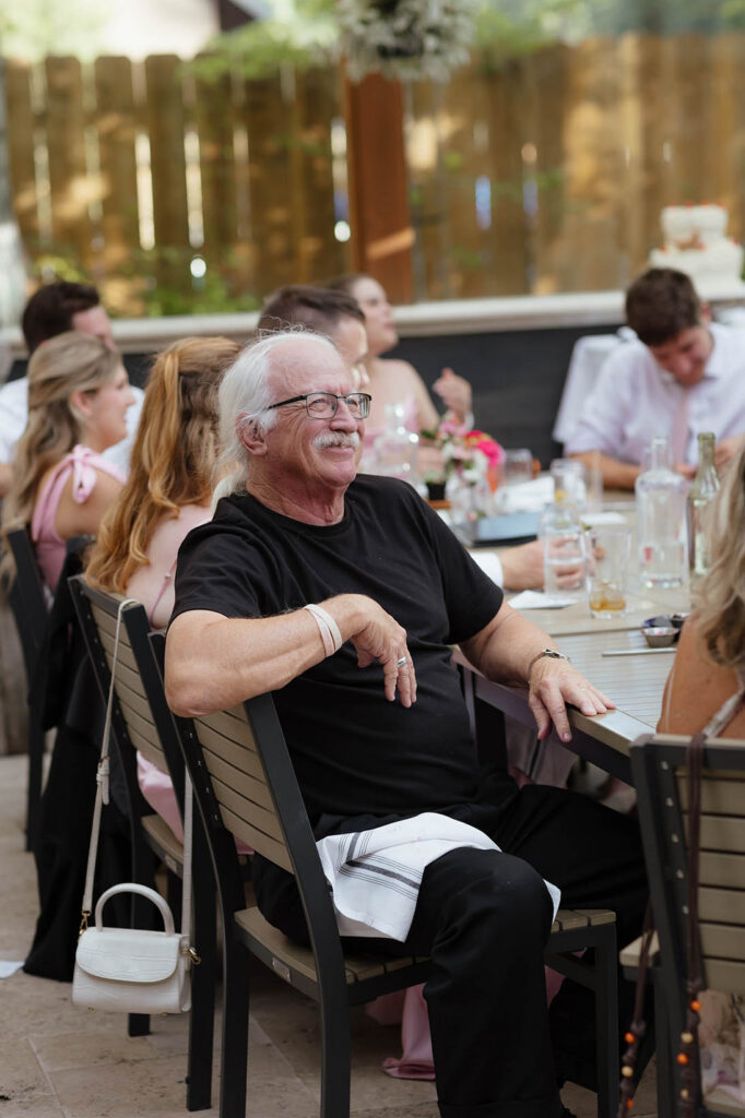 A smiling wedding guest listens to speeches during the couple’s South Lake Tahoe reception