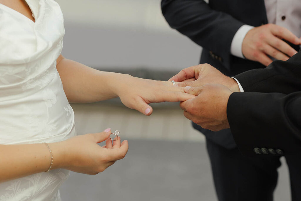 Close-up of the groom placing a wedding ring on the bride’s finger