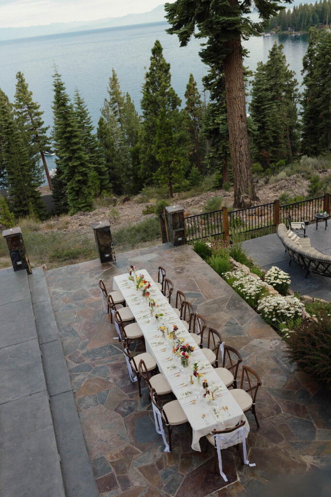 Long outdoor reception table decorated with colorful flowers overlooking Lake Tahoe