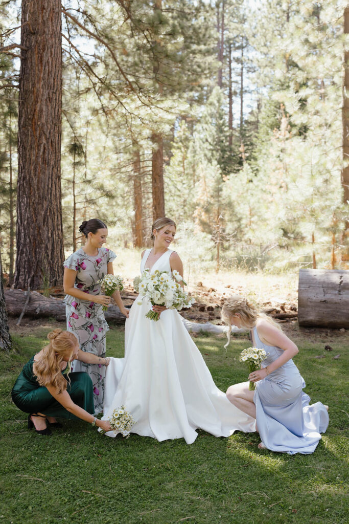 Bridesmaids arrange the bride’s gown and train in the forest at Valhalla Tahoe