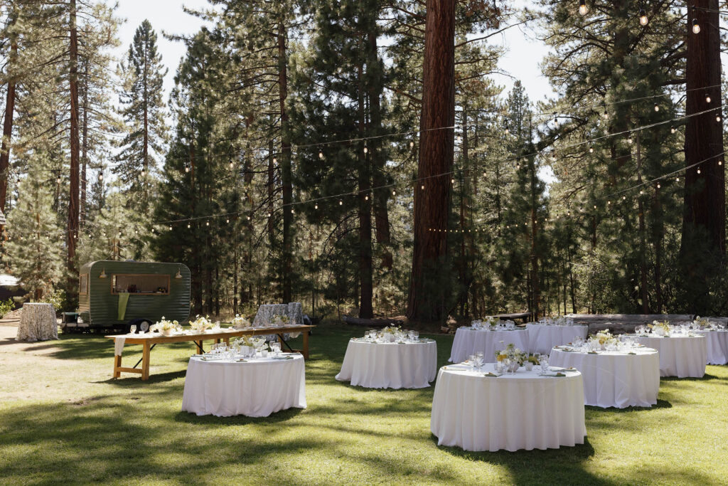 Outdoor Valhalla Tahoe reception with white tables and string lights beneath the pine trees