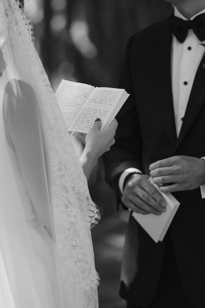 Black-and-white close-up of the bride reading handwritten vows to the groom
