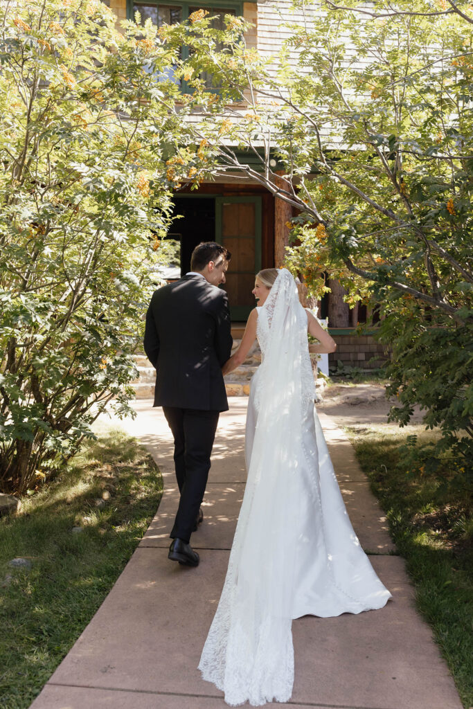 Bride and groom walk hand in hand toward a rustic cabin at Valhalla Tahoe