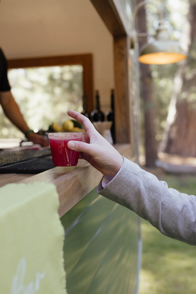 Guest picks up a bright red signature cocktail from the mobile bar