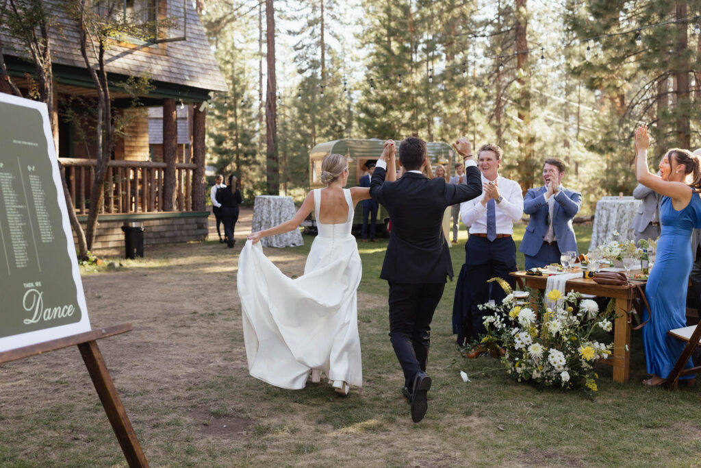 Bride and groom enter the outdoor reception as cheering guests welcome them