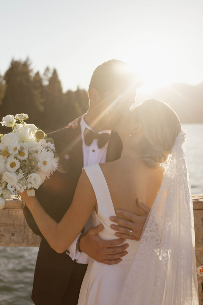 Bride and groom share a sunlit kiss by the lake at Valhalla Tahoe