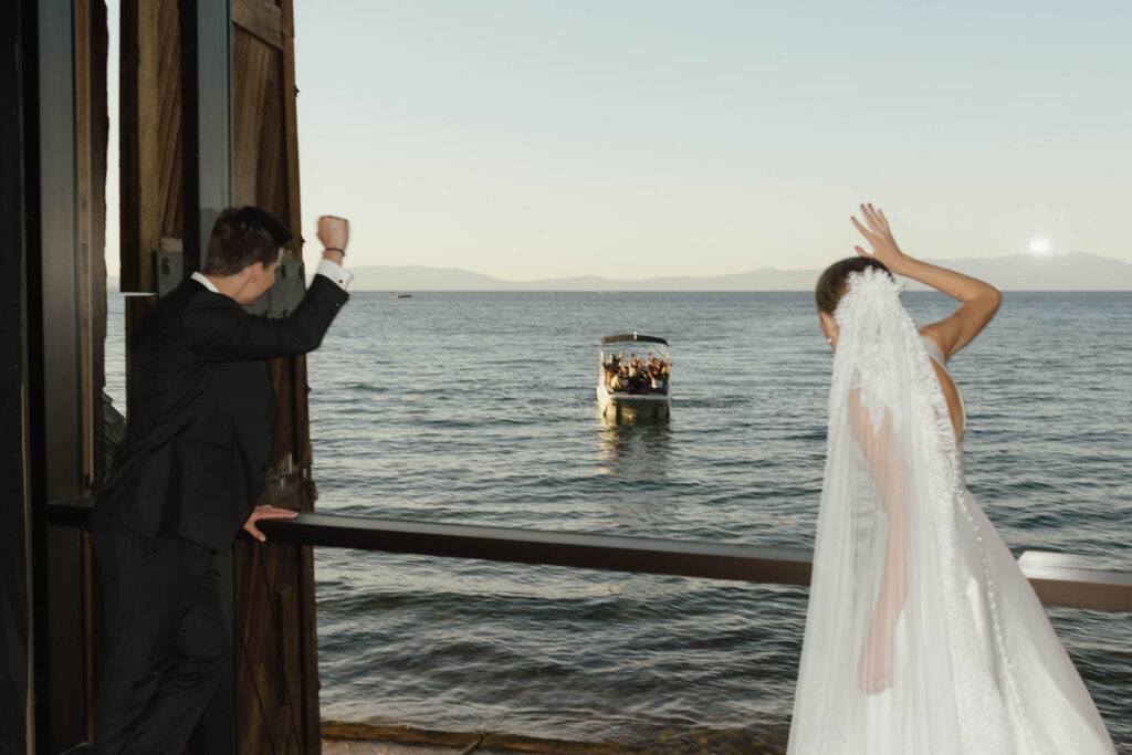 Newlyweds wave to passengers on a boat from the Valhalla Tahoe shoreline