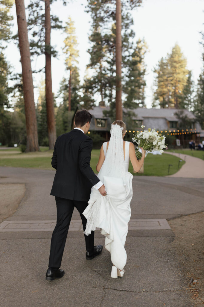 Bride and groom walk toward the Valhalla Tahoe lodge after their lakeside portraits