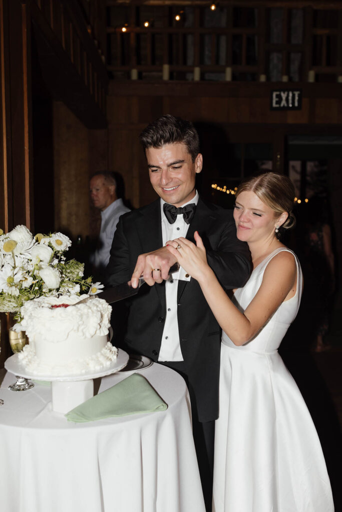 Bride and groom cut their wedding cake inside the rustic Valhalla Tahoe reception hall