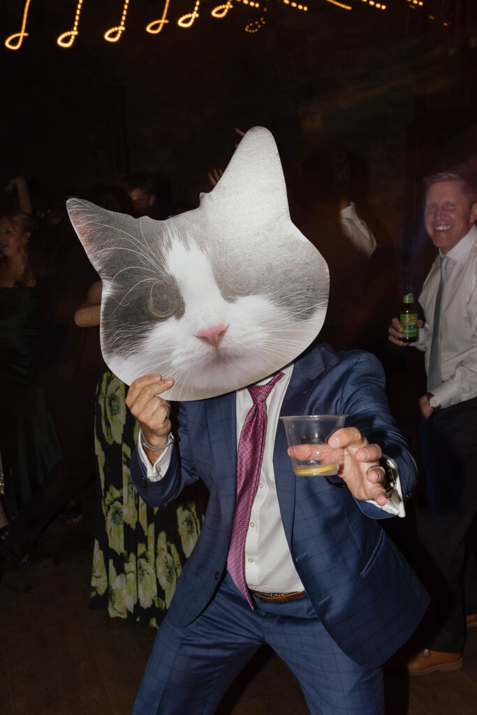 Guest in a blue suit dances behind an oversized cat portrait at the reception