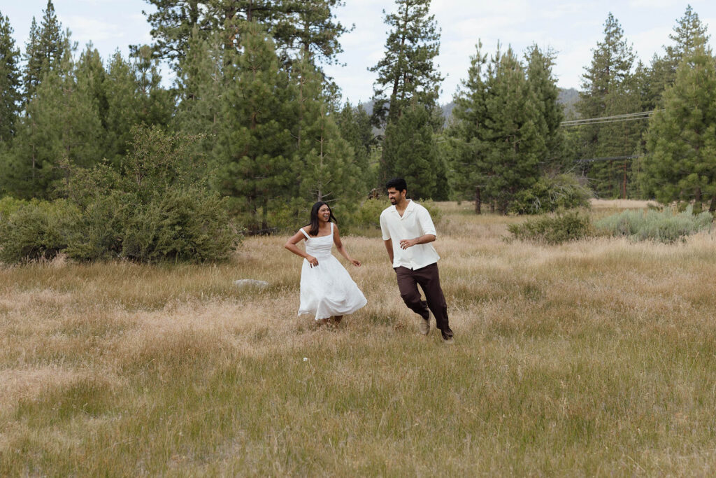 Laughing couple running through a grassy meadow during their South Lake Tahoe engagements
