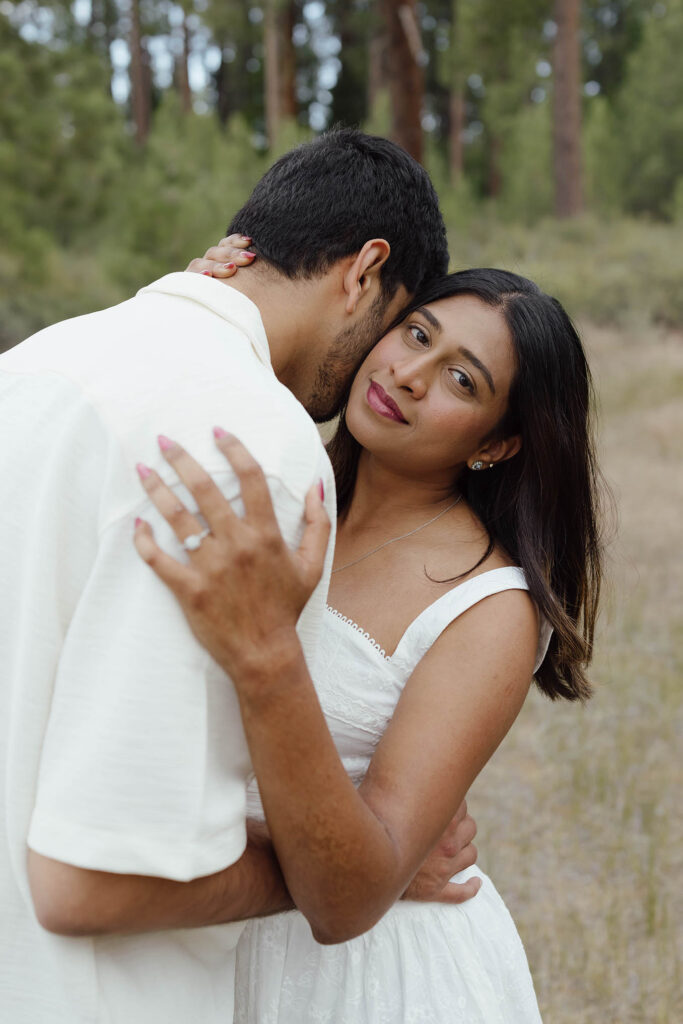 Woman showing her engagement ring while hugging her fiancé during their South Lake Tahoe engagement session