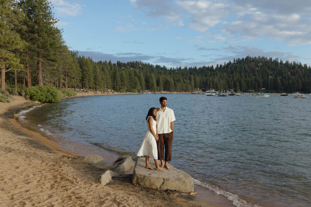 Couple standing barefoot on a shoreline boulder during their South Lake Tahoe engagement session