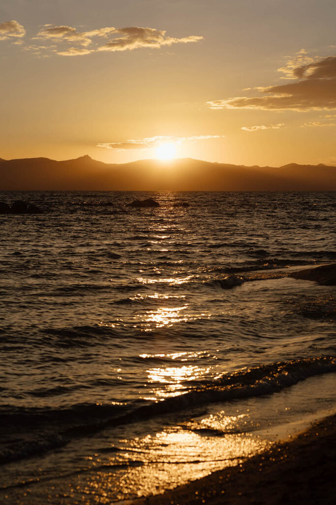 Golden summer sunset reflecting across the water and mountains of Lake Tahoe