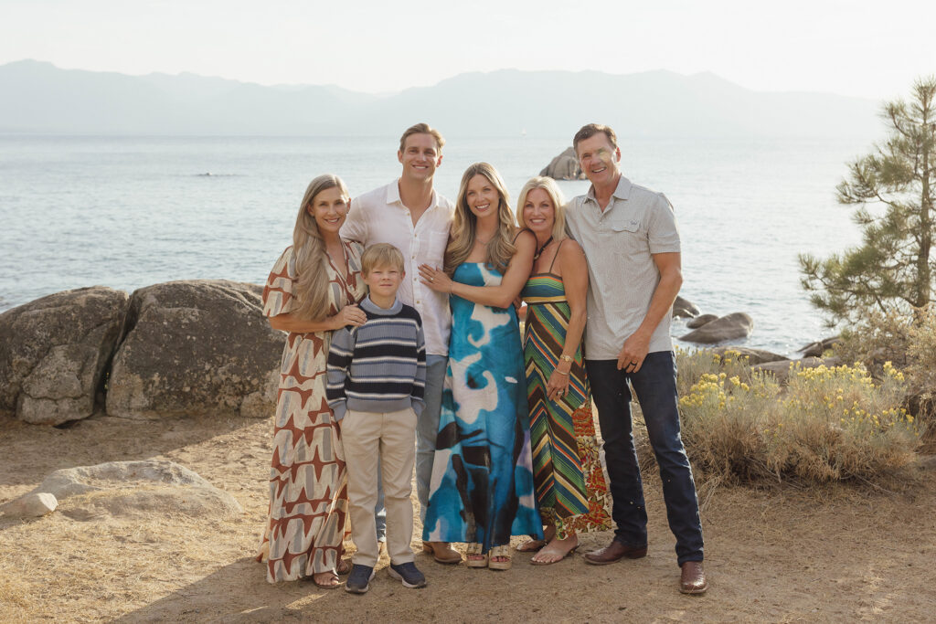 Newly engaged couple posing with family in Lake Tahoe, with granite boulders and mountains behind them