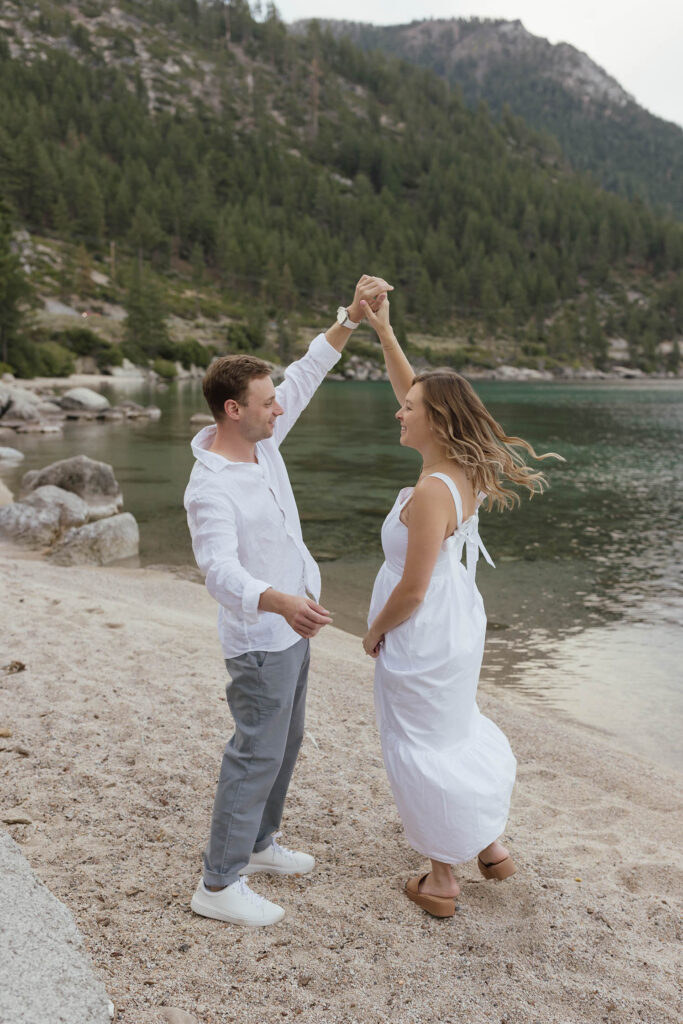 Fiancé twirling his bride-to-be on a sandy Lake Tahoe beach during their engagement session