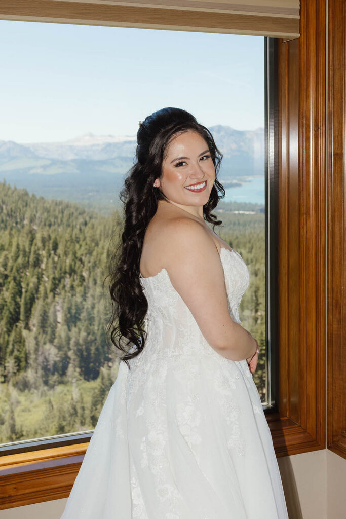 Bride posing beside a window overlooking Lake Tahoe during her Tahoe Blue Estate wedding