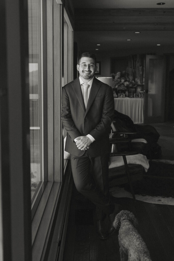 Black-and-white portrait of the groom in his wedding suit beside a window at Tahoe Blue Estate
