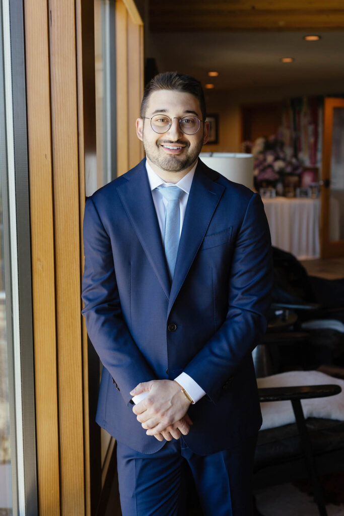 Groom smiling in a navy blue suit and light blue tie before the Lake Tahoe wedding ceremony
