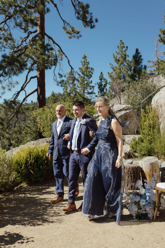 Groom walking arm in arm with family members before the outdoor Lake Tahoe wedding ceremony