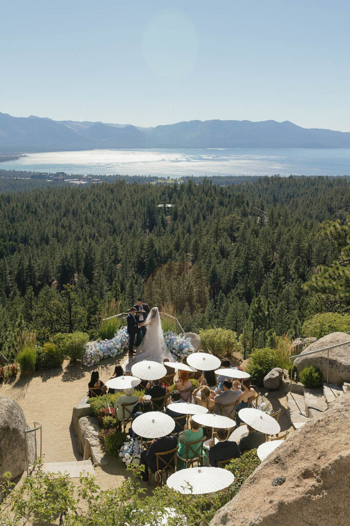 Intimate Tahoe Blue Estate wedding ceremony overlooking Lake Tahoe with guests holding white umbrellas
