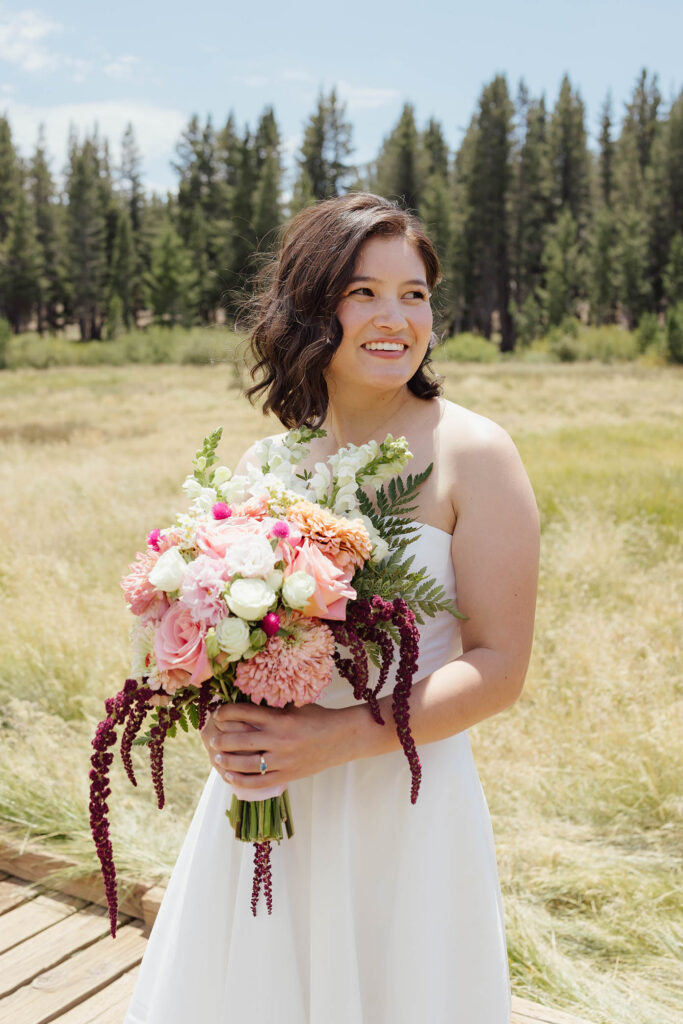 Smiling bride holding a pink, peach, white and burgundy bouquet during her Lake Tahoe bridal portraits