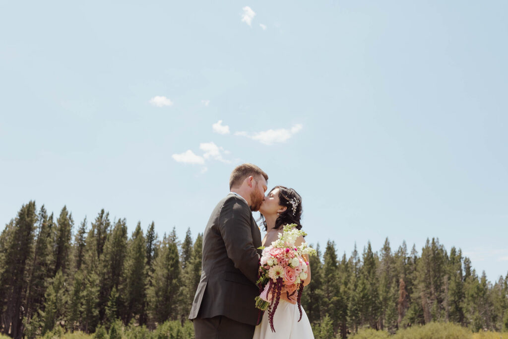 Bride and groom kissing in a mountain meadow during adventure bridals before their Winters Creek Lodge wedding