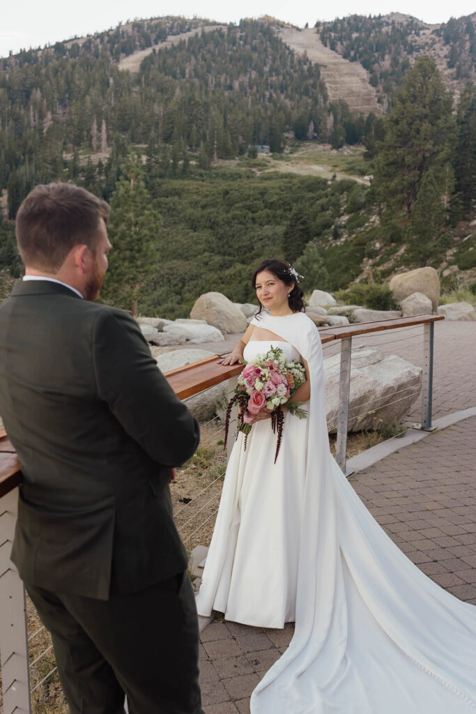 Bride holding her bouquet and looking toward the groom on the mountain terrace at Winters Creek Lodge near Lake Tahoe