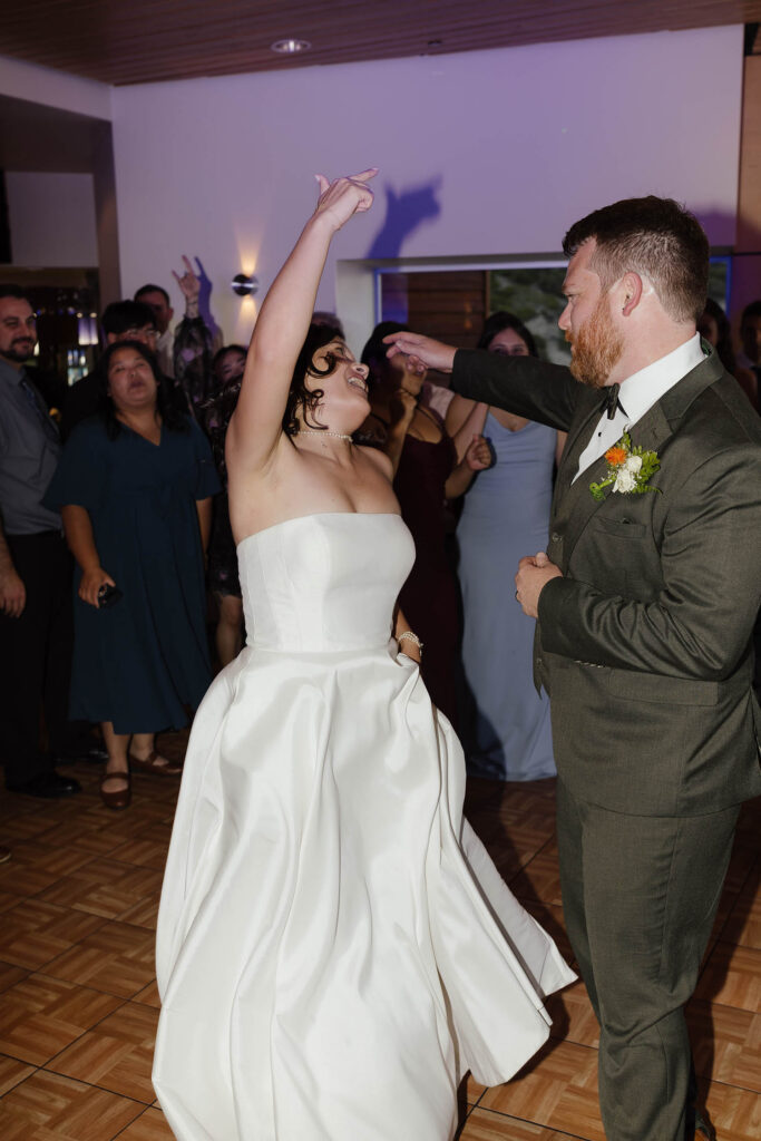 Bride raising her arm while dancing with the groom and guests during their Winters Creek Lodge wedding reception